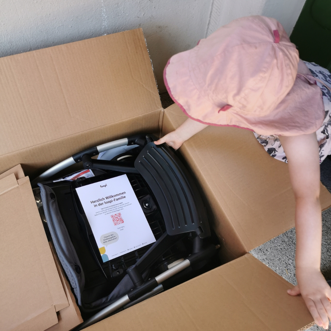 Kind öffnet loopi Lieferung mit Kinderwagen